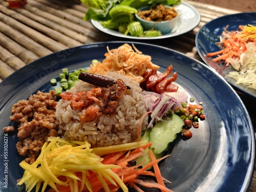 Fried rice with shrimp paste on a bamboo table is a traditional Thai dish that can easily be found in Thai restaurants. Rice mixed with Shrimp Paste, Khao kluk kapi.