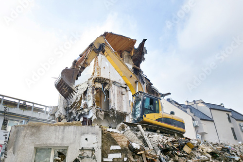 Dismantling old residential building with excavator