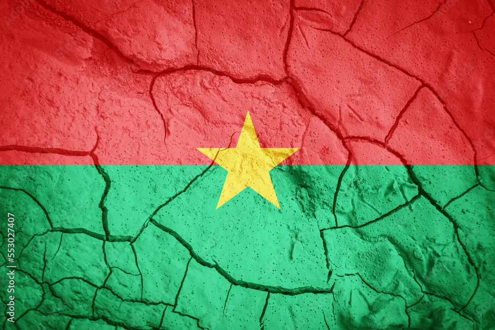 Flag of Burkina Faso. Burkina Faso symbol. Flag on the background of dry cracked earth. Burkina Faso flag with drought concept