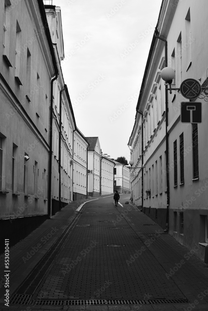 Narrow street of an old European city. Black and white photo in the style of film photography.