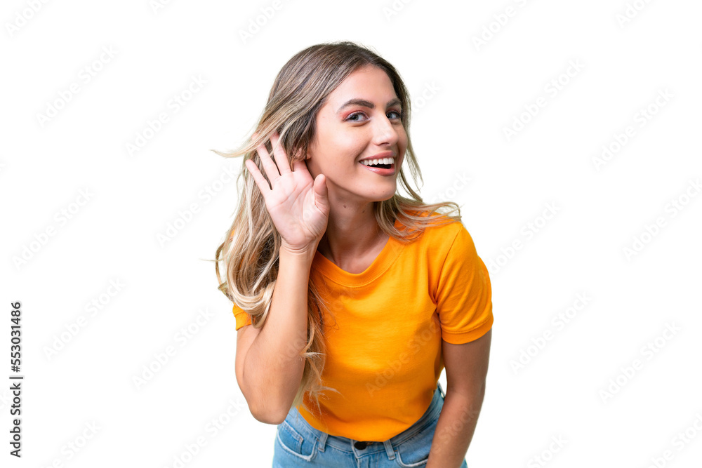 Young Uruguayan woman over isolated background listening to something by putting hand on the ear - obrazy, fototapety, plakaty 