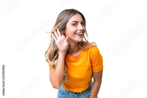 Foto Young Uruguayan woman over isolated background listening to something by putting