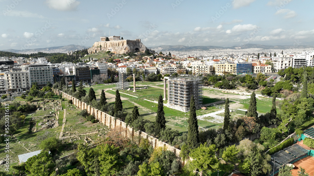 Aerial drone photo of iconic ruins of Temple of Olympian Zeus at sunset and world famous Acropolis hill and the Parthenon at the background, Athens, Attica, Greece