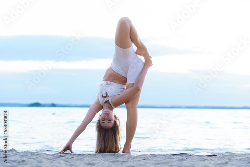 Young woman doing complex Yoga exercise headstand with Namaste a