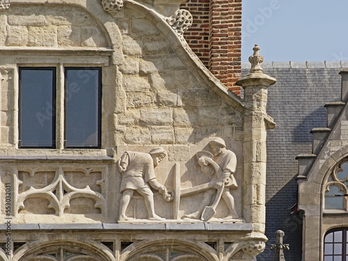 Bas relief sculpture of dockworkers holding an anchor on a medieval guild house in the port of Ghent photo