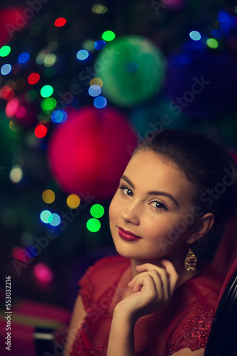 Close-up beautiful portrait of a young girl with a festive make-up against the background of New Year's lights in bokeh