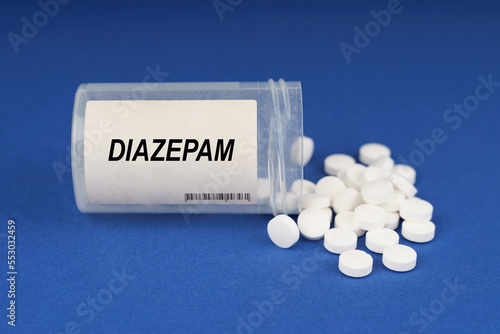 On a blue surface are pills and a dusty jar with the inscription - Diazepam photo