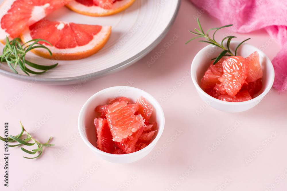 Juicy grapefruit slices and rosemary in a bowl on the table. Cocktail ingredients. Juicy grapefruit slices and rosemary in a bowl on the table. Cocktail ingredients.
