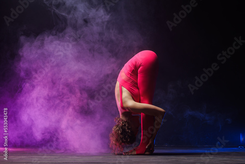 the girl is engaged in stretching on a dark background, a stylish photo of fitness and yoga. Copy space