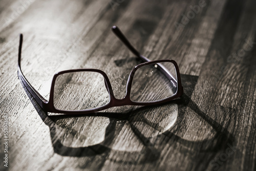 Old glasses with shadow on wooden table surface closeup
