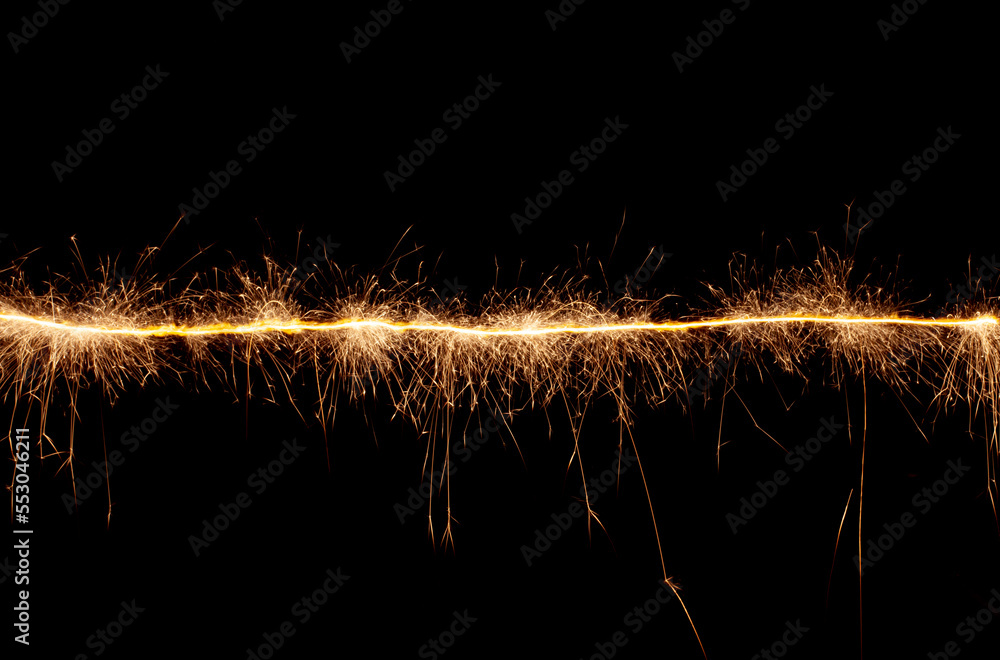 Fototapeta premium A line of sparks on a black background. Bengal light moving in the dark.