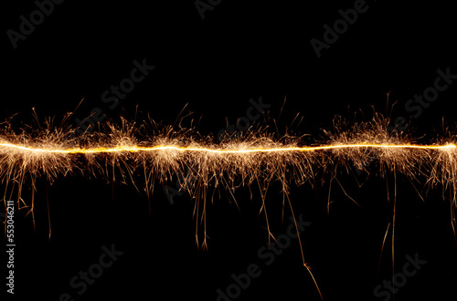 A line of sparks on a black background. Bengal light moving in the dark.