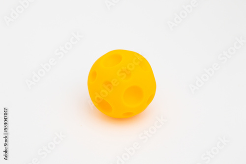Rubber tactile ball, educational toy for babies. Yellow ball with indentations on a white background