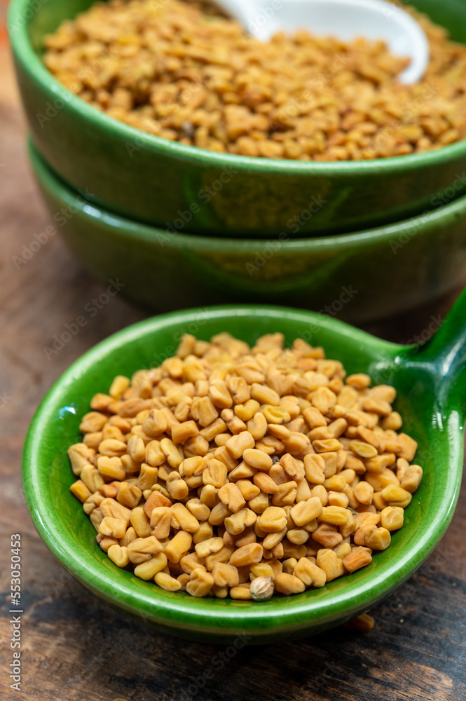 Indian spices collection, dried aromatic fenugreek seeds and another spices in clay green bowl