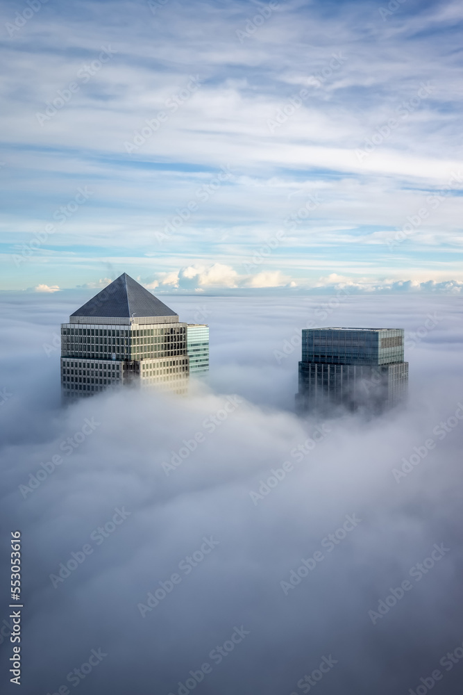 Φωτογραφία The modern skyline of Canary Wharf, London, during a foggy day with the tops of