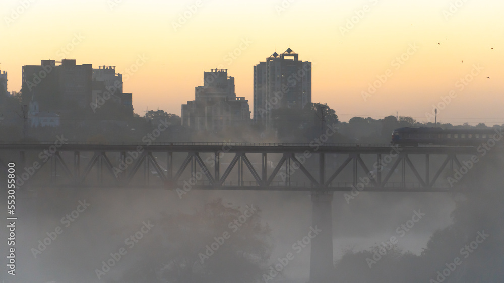 railway bridge in the fog. Train movement on the bridge over the river during fog on the background of sunrise