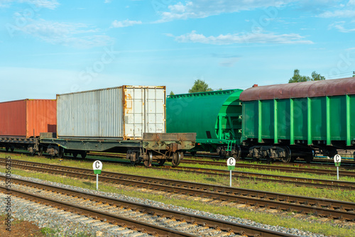 Cargo transportation by rail. There is a transport train with containers on the railway track. Logistics, transportation of essential goods, grain, fuel, industrial goods.
