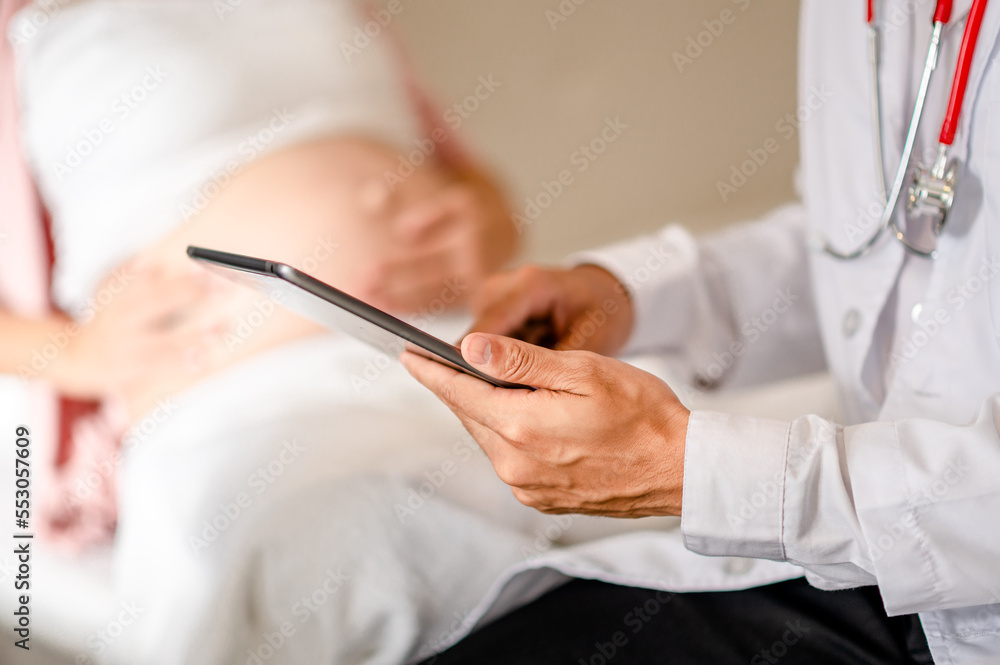 Close up of Male doctor hold patient have consultation with pregnant woman in hospital. Female gynecologist talk consult female check pregnancy before giving birth. Maternity concept. Close up of Male doctor hold patient have consultation with pregnant woman in hospital. Female gynecologist talk consult female check pregnancy before giving birth. Maternity concept.