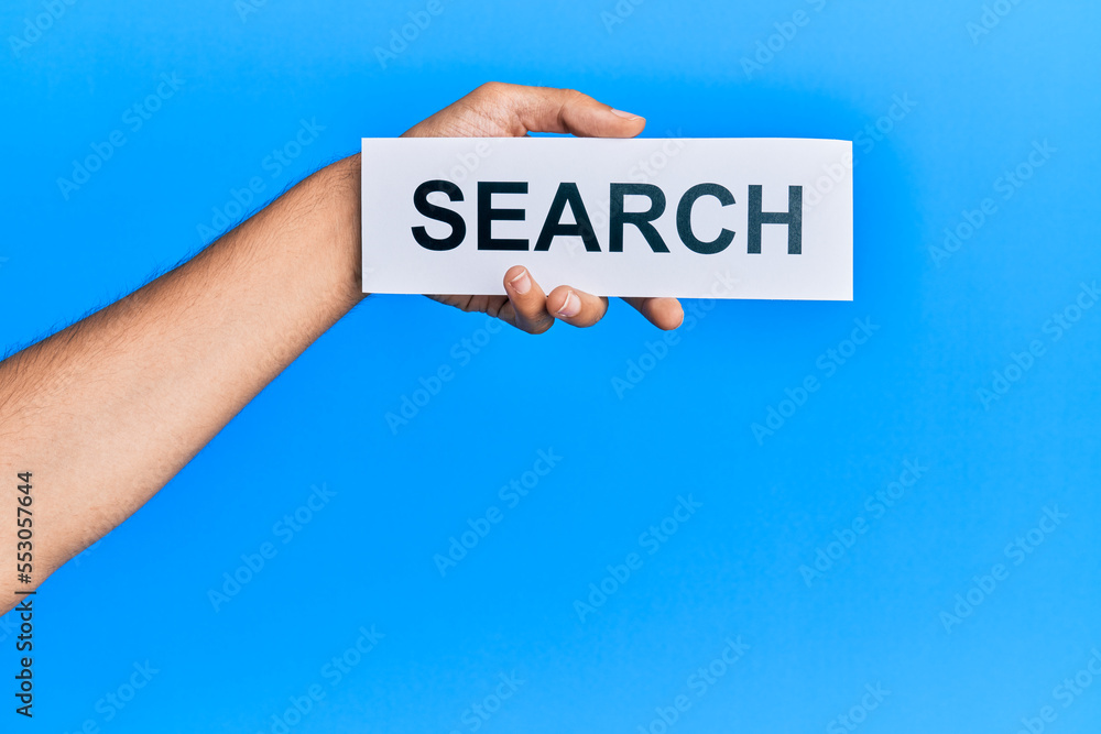 Hand of caucasian man holding paper with search word over isolated blue background Hand of caucasian man holding paper with search word over isolated blue background