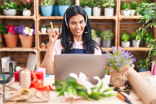 Mature hispanic woman working at florist shop doing video call smiling with an idea or question pointing finger with happy face, number one © Krakenimages.com