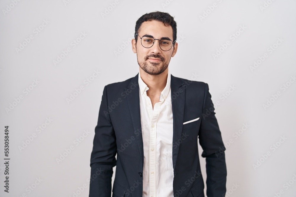 Handsome business hispanic man standing over white background relaxed with serious expression on face. simple and natural looking at the camera. Handsome business hispanic man standing over white background relaxed with serious expression on face. simple and natural looking at the camera.