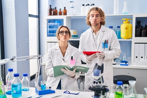 Two people working at scientist laboratory looking at the camera blowing a kiss being lovely and sexy. love expression.