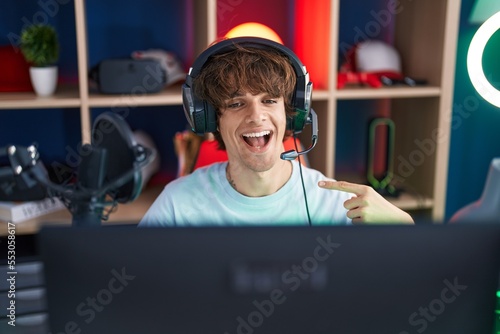 Hispanic young man playing video games smiling happy pointing with hand and finger
