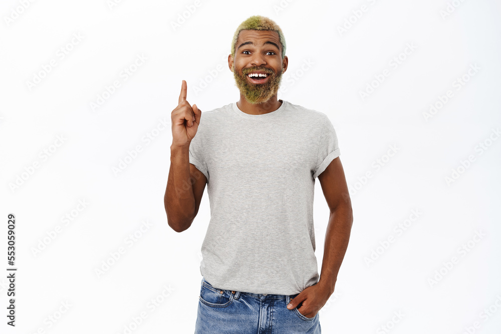 Handsome stylish Black man with yellow beard, pointing fingers up, showing advertising, promo text on top, white background Handsome stylish Black man with yellow beard, pointing fingers up, showing advertising, promo text on top, white background