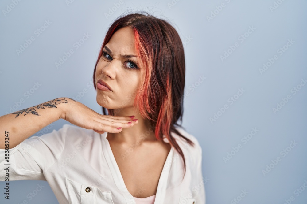 Young caucasian woman wearing casual white shirt over isolated background cutting throat with hand as knife, threaten aggression with furious violence Young caucasian woman wearing casual white shirt over isolated background cutting throat with hand as knife, threaten aggression with furious violence