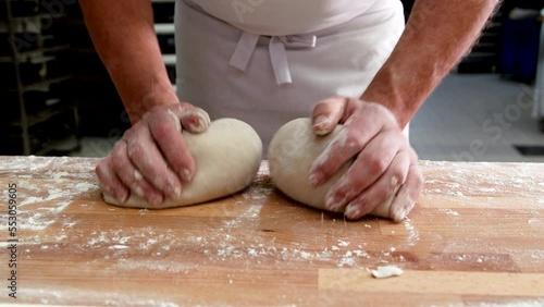 Bäcker formt mit der Hand Teiglinge um danach Brot zu backen photo