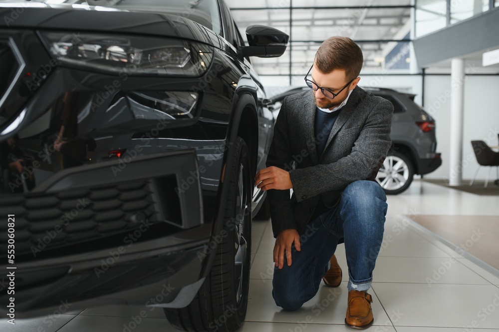 Man adult customer male buyer client wears classic suit white shirt chooses auto wants to buy new automobile touch check car in showroom vehicle salon dealership store motor show indoor. Sales concept Man adult customer male buyer client wears classic suit white shirt chooses auto wants to buy new automobile touch check car in showroom vehicle salon dealership store motor show indoor. Sales concept