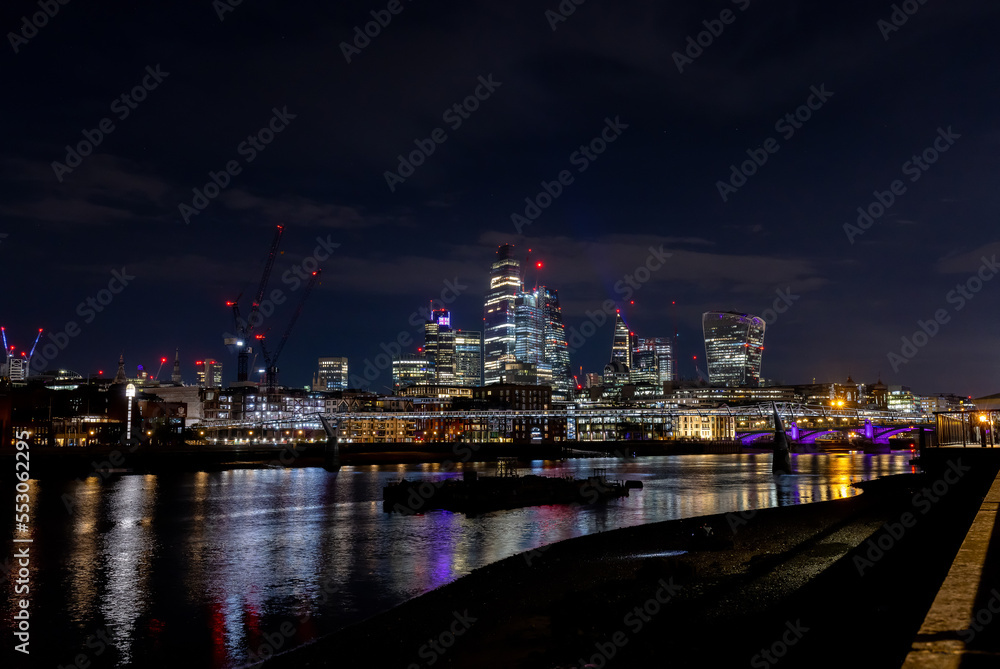 Beautiful view of London city landscape from Thames waterfront at night, handheld shot. Rapid growth and urban development concept.
