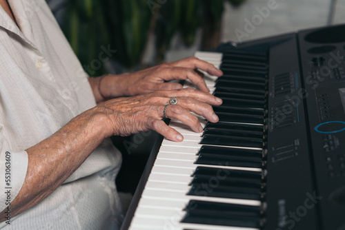 Horizaontal image of a unrecognizable old person playing the piano keyboard.	 photo