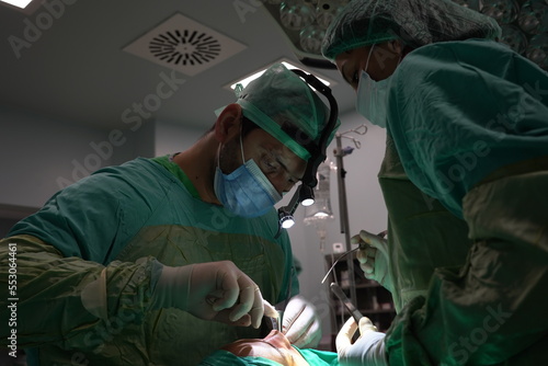 Doctor performing nose surgery in the operating room. green dresses and black room in the operating room 