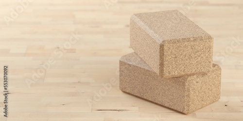 Two stacked yoga or pilates blocks made from natural cork on wooden floor background in yoga, pilates or fitness studio with copy space
