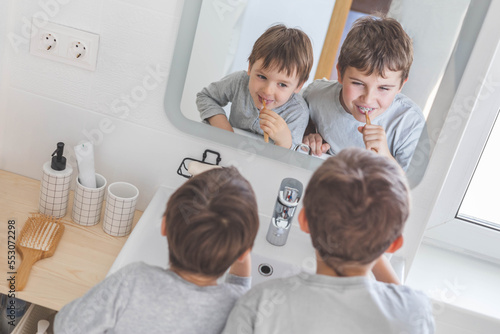 Brother morning fun male kids cleaning teeth toothbrush in front of mirror sink at bathroom