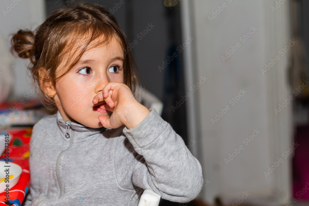 Little girl with brown hair and gray sweatshirt looking to the side of