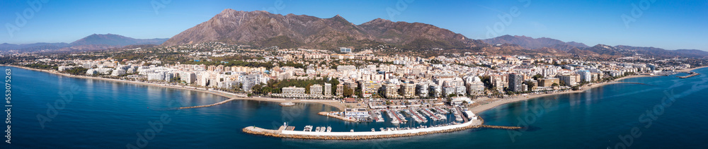 Scenic panoramic view of Spanish coastal city of Marbella by Mediterranean sea in foothills of Sierra Blanca mountain range overlooking harbour 