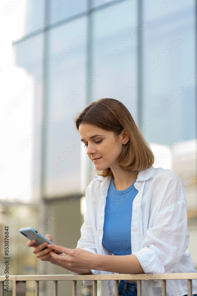 Young caucasian woman using mobile phone chatting, reading text message outdoors Young caucasian woman using mobile phone chatting, reading text message outdoors