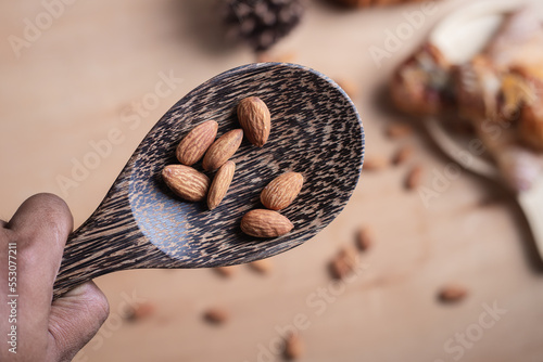 Closeup of almonds in wooden spoon with bread on wooden background, vintage tones, breadbread
 photo