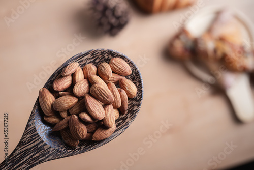 Closeup of almonds in wooden spoon with bread on wooden background, vintage tones, breadbread
 photo