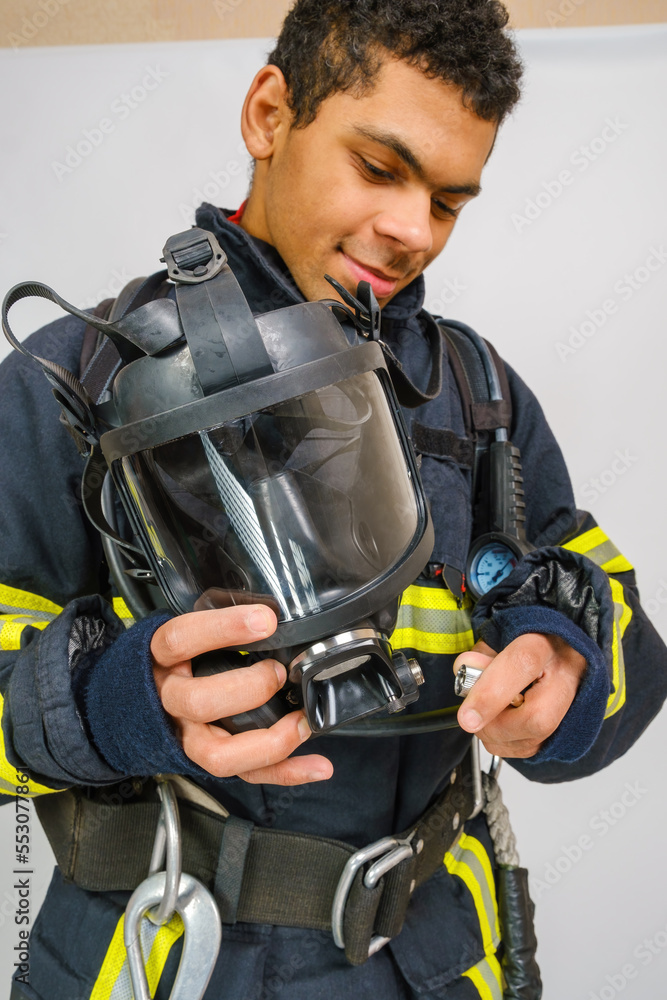 Full protective breathing air mask in hand of unrecognizing African American firefighter, rescue and fire fighter equipment, vertical orientation Full protective breathing air mask in hand of unrecognizing African American firefighter, rescue and fire fighter equipment, vertical orientation