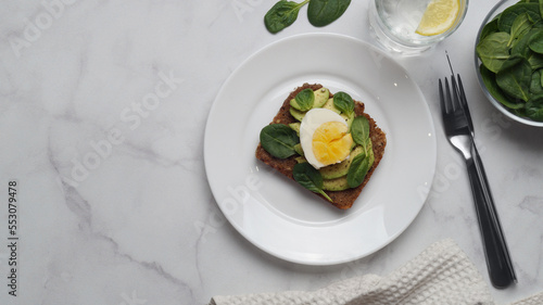 Tasty sandwich with boiled egg, avocado and spinach served on white marble table, flat lay. Space for text