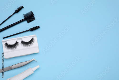 Flat lay composition with fake eyelashes on light blue background  space for text