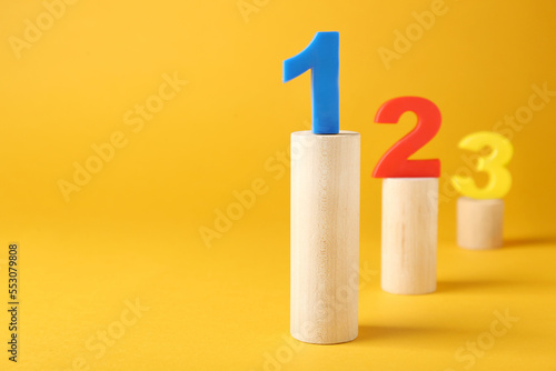 Numbers on wooden blocks against pale orange background, space for text. Competition concept photo