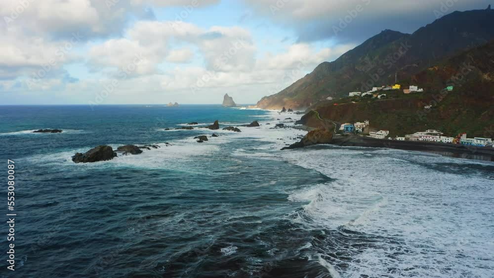 Rocky beach on Tenerife north with blue deep ocean water and volcanic wild shoreline Benijo Beach. Black frozen lava stones, sea foam scenery. Cloudy sky at sunset. Tourist attraction. Aerial. Rocky beach on Tenerife north with blue deep ocean water and volcanic wild shoreline Benijo Beach. Black frozen lava stones, sea foam scenery. Cloudy sky at sunset. Tourist attraction. Aerial.