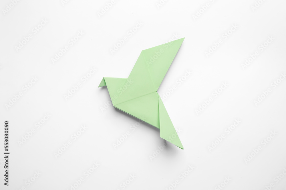 Fototapeta premium Beautiful light green origami bird on white background, top view