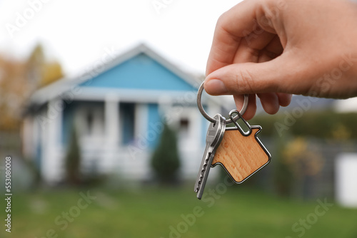 Woman holding house keys outdoors, closeup with space for text. Real estate agent