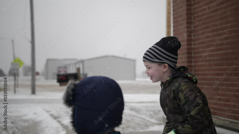 Happy, smiling, young boys play outside in the snow on a cold winter day in December during Christmas break.