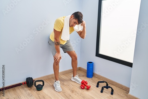 Young hispanic man leaning on wall resting at sport center